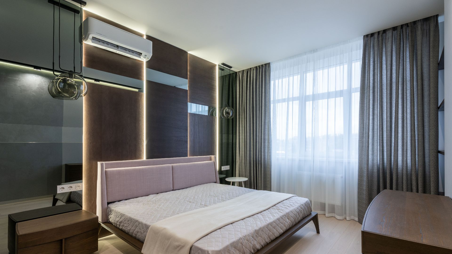 Comfortable bed with wooden nightstand and chest of drawers in modern bedroom decorated with curtains and lamps