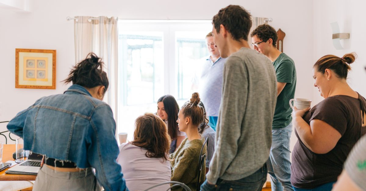 A group of adults collaborating around a table in a bright room, promoting teamwork and creativity.