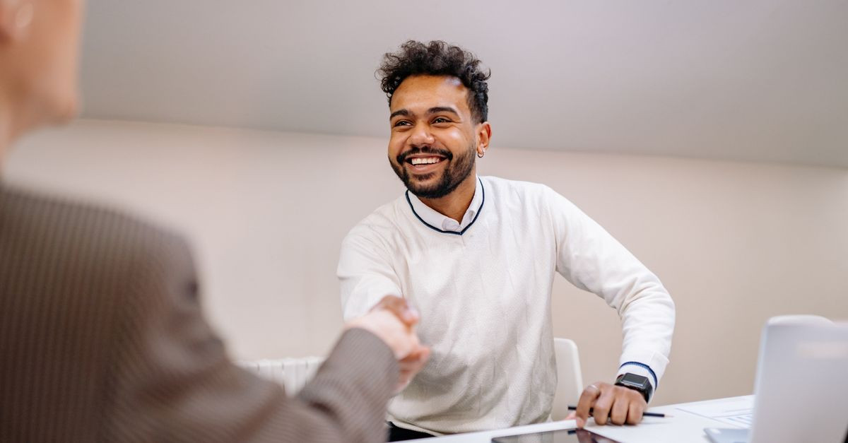 Smiling businessman shaking hands in a modern office. Professional teamwork and agreement concept.
