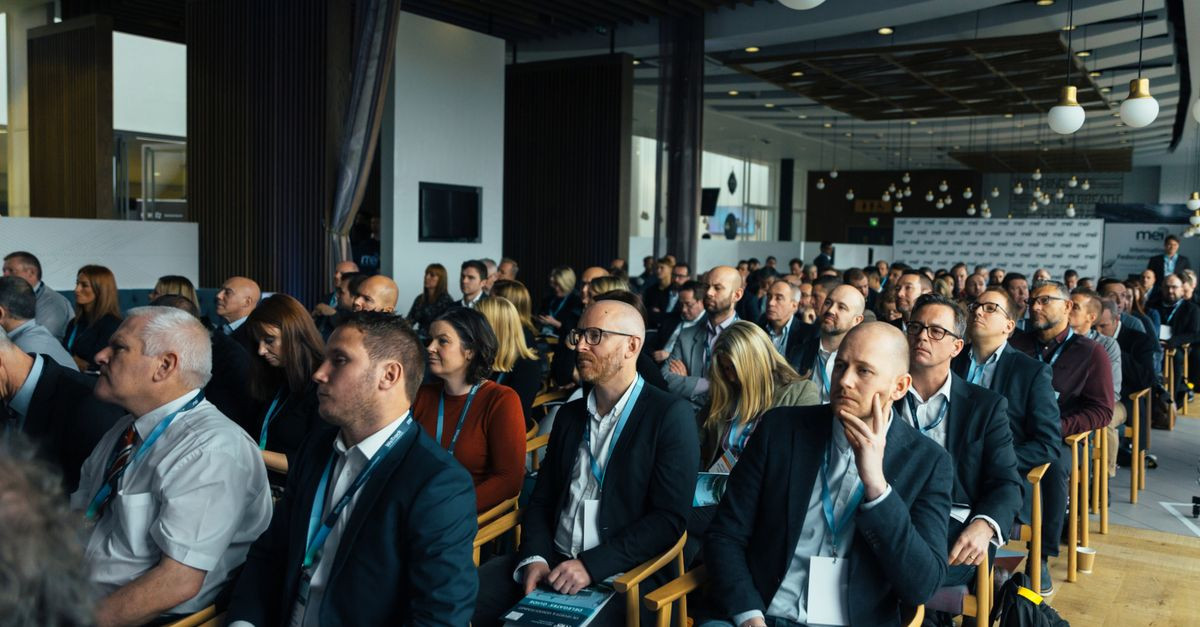 Business professionals attentively listening at an indoor conference meeting.