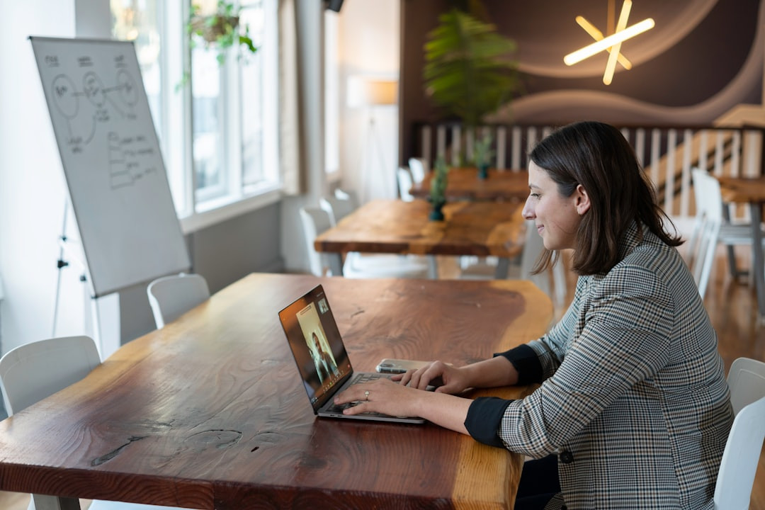 A woman in a plaid blazer on a video call using a laptop