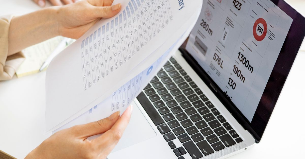Modern office setting with a business report and laptop display on a white desk.