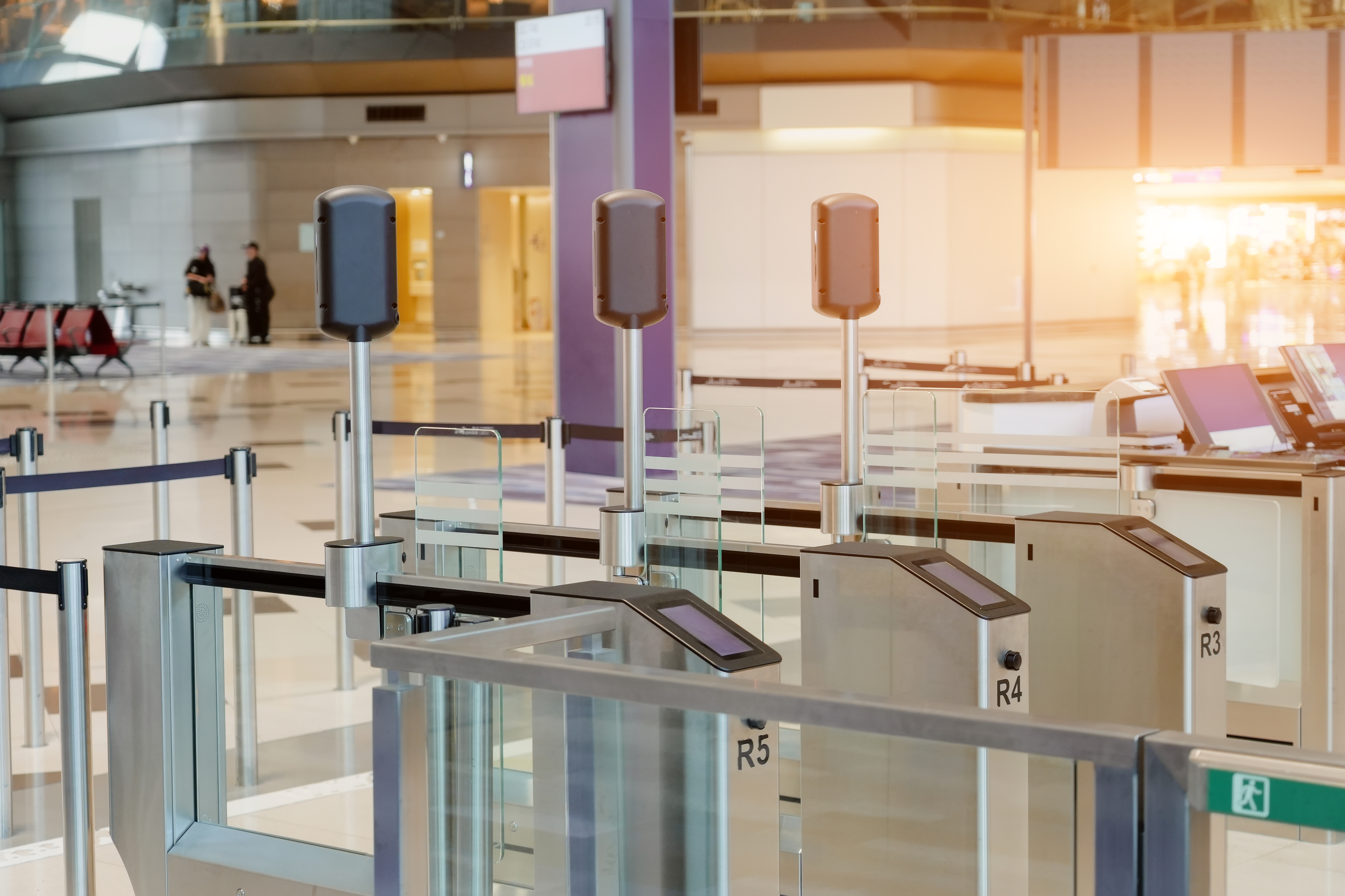 Automated e-gates with electronic screens are open for passenger entry at a modern airport terminal during daytime