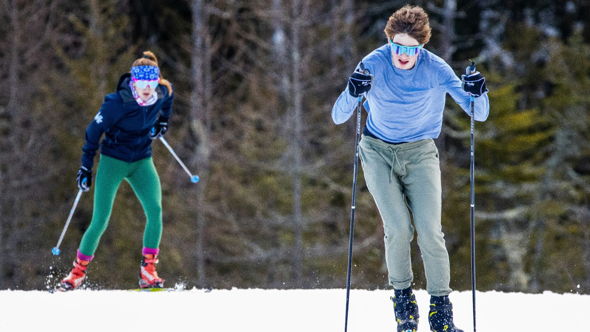 a couple of people riding skis down a snow covered slope