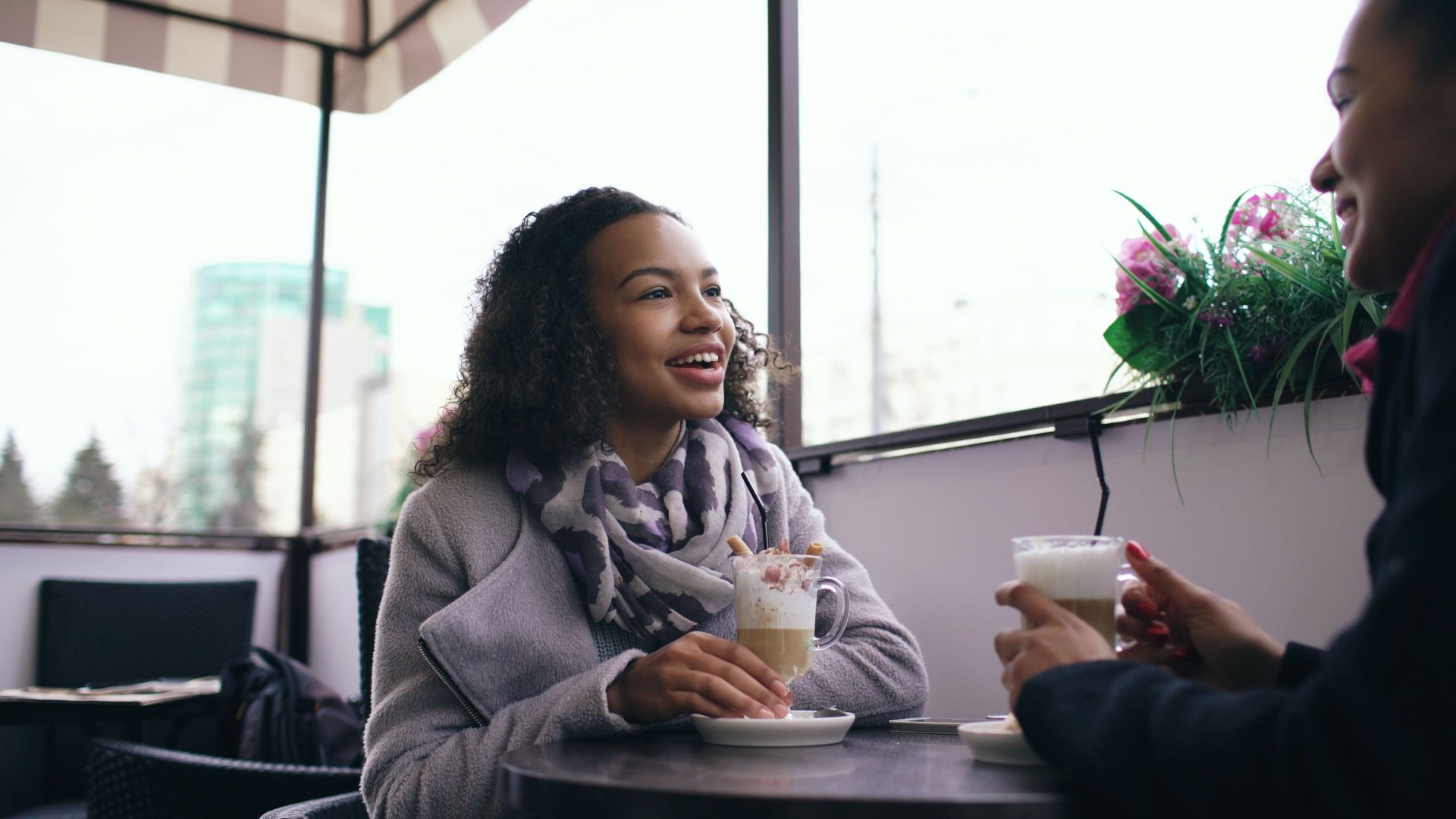 Two women enjoying coffee and conversation at an outdoor cafe.