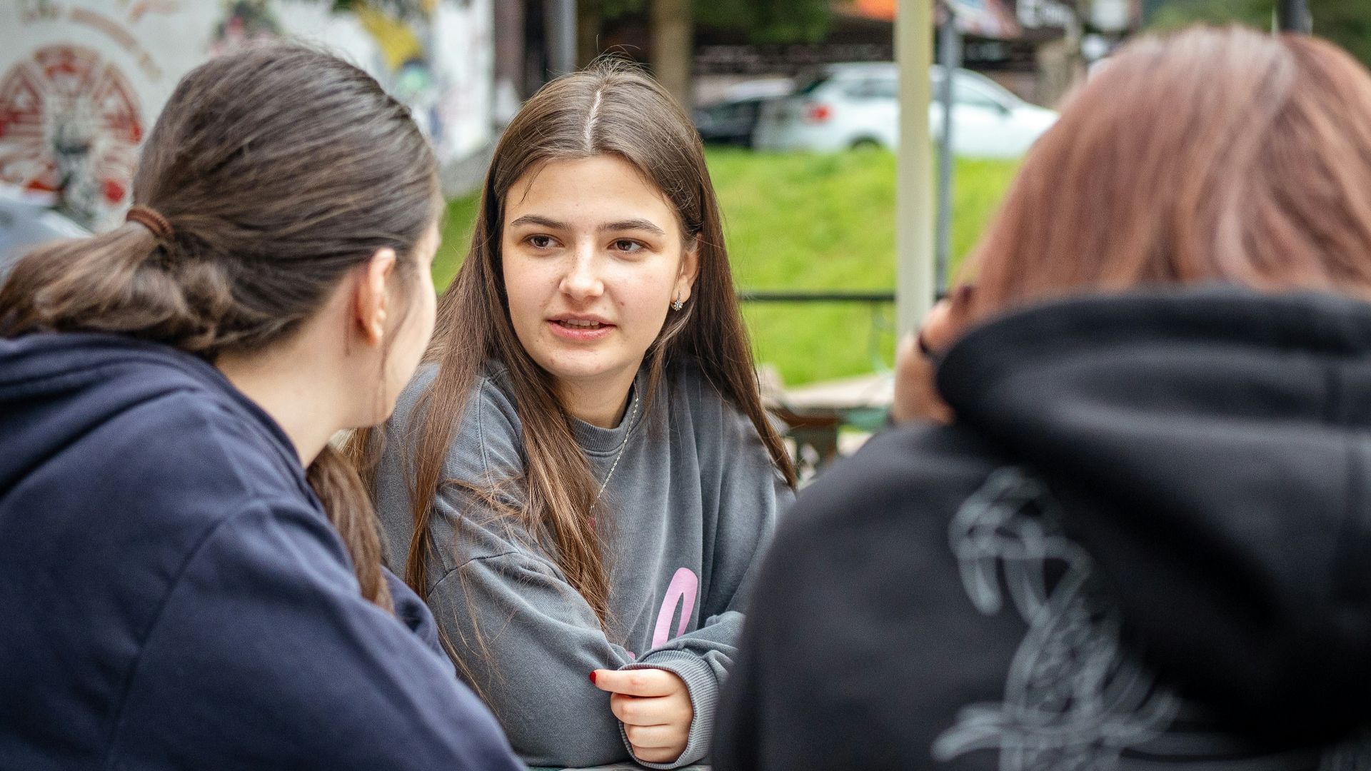 Three young women talking at an outdoor table