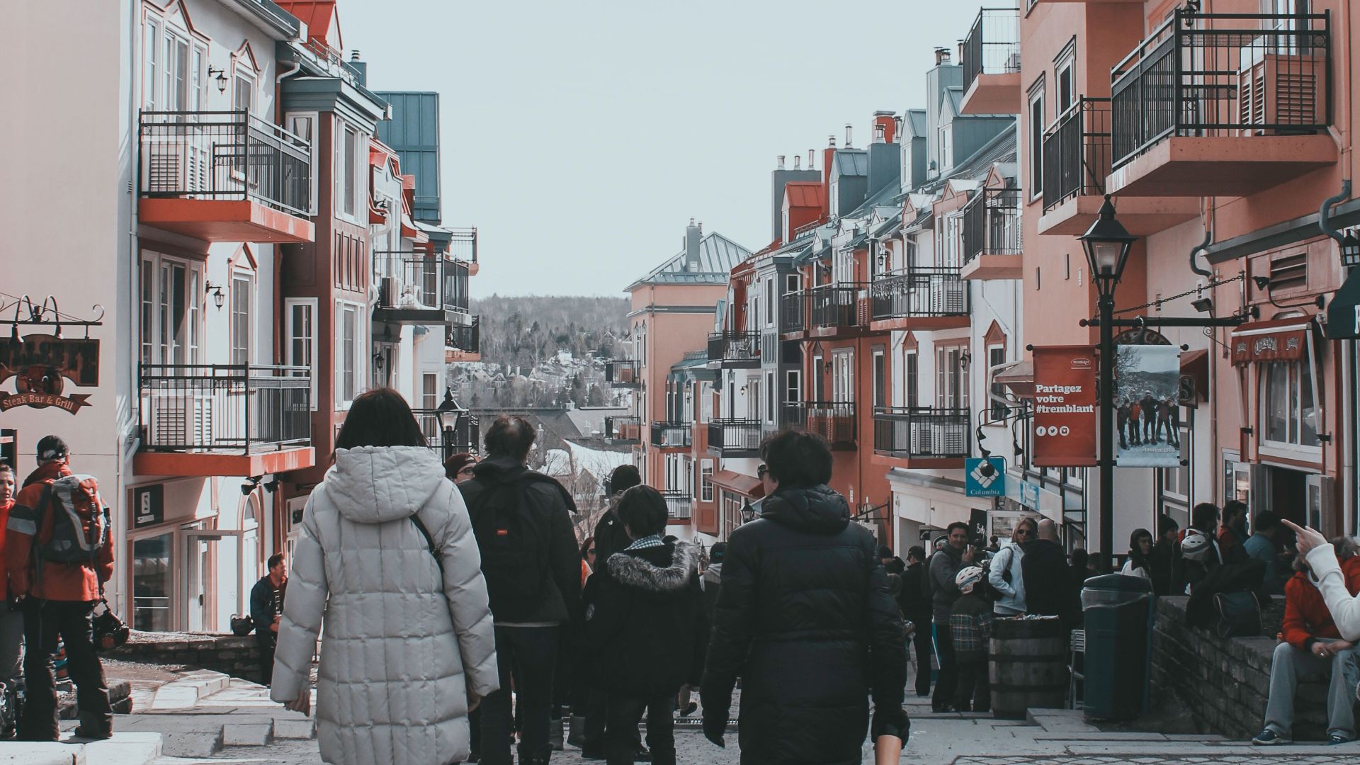 People walking in Mont-Tremblant's lively winter village street, surrounded by colorful buildings.