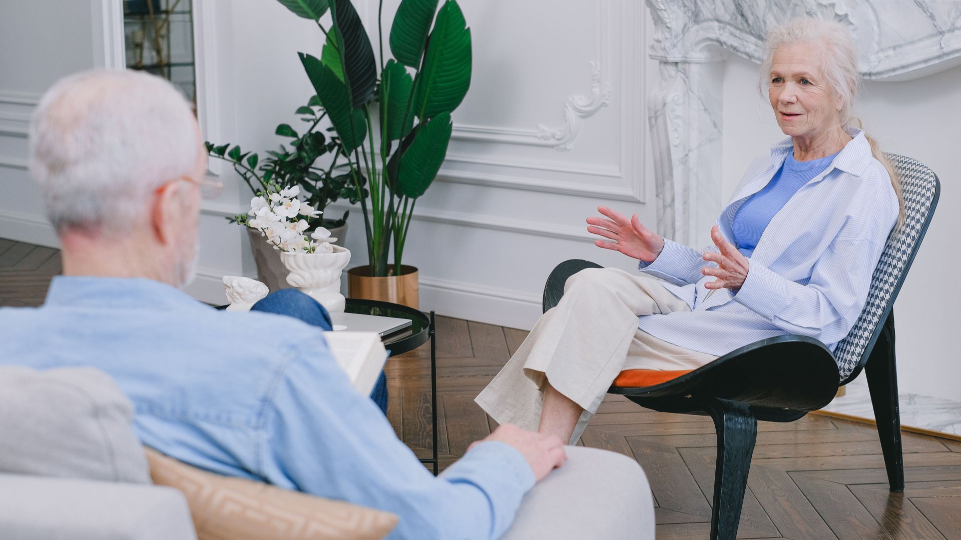 Elderly couple discussing in a stylish living room with plants.