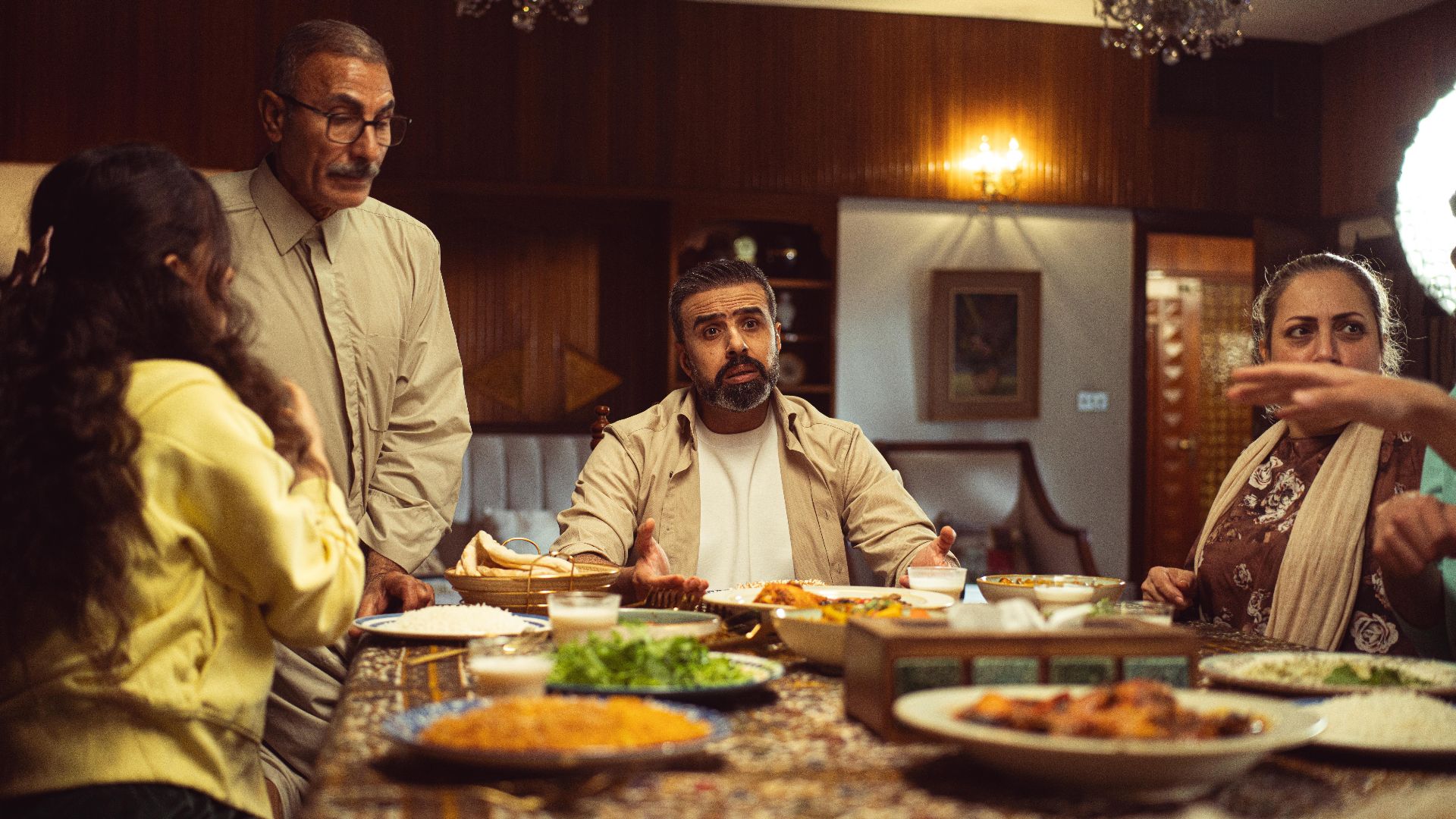 A family gathers around a dinner table in a cozy indoor setting, engaging in lively conversation.