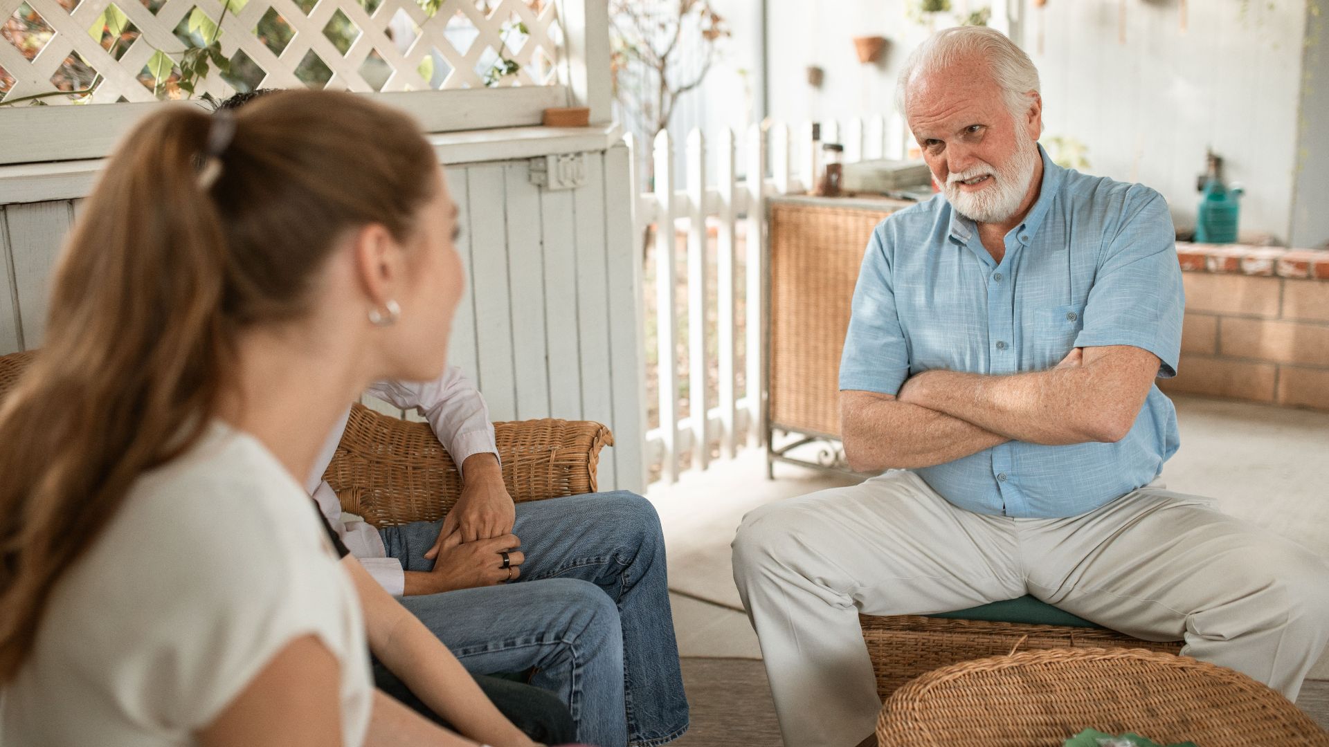 Senior man and two adults having a friendly conversation on a spacious veranda.