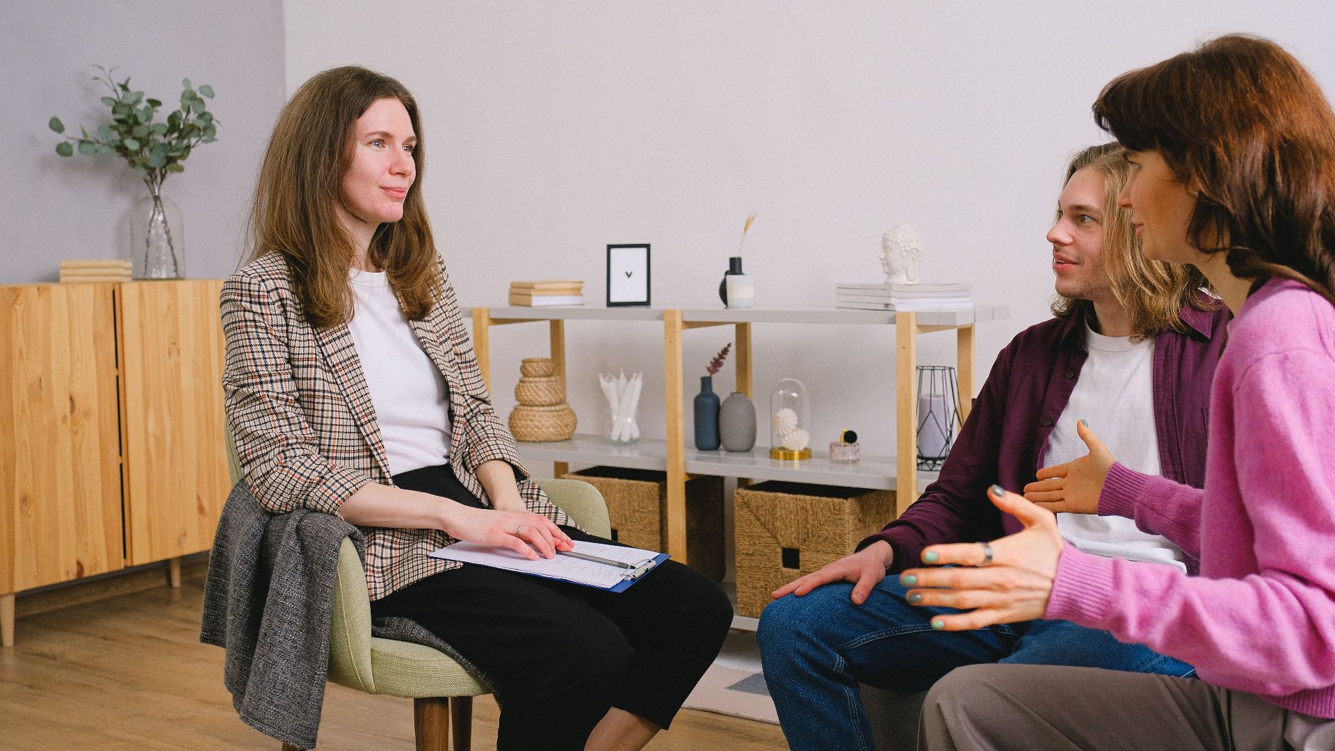 Young adults discuss with a counselor during an indoor therapy session.