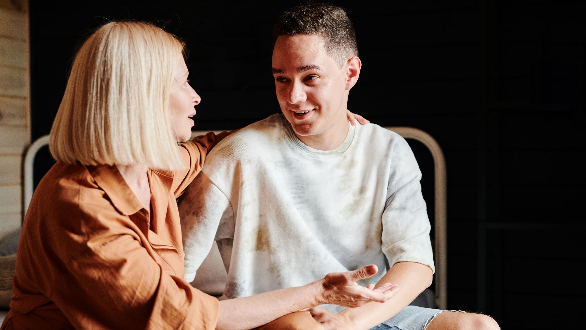 A mother and son engage in a warm, heartfelt conversation indoors.