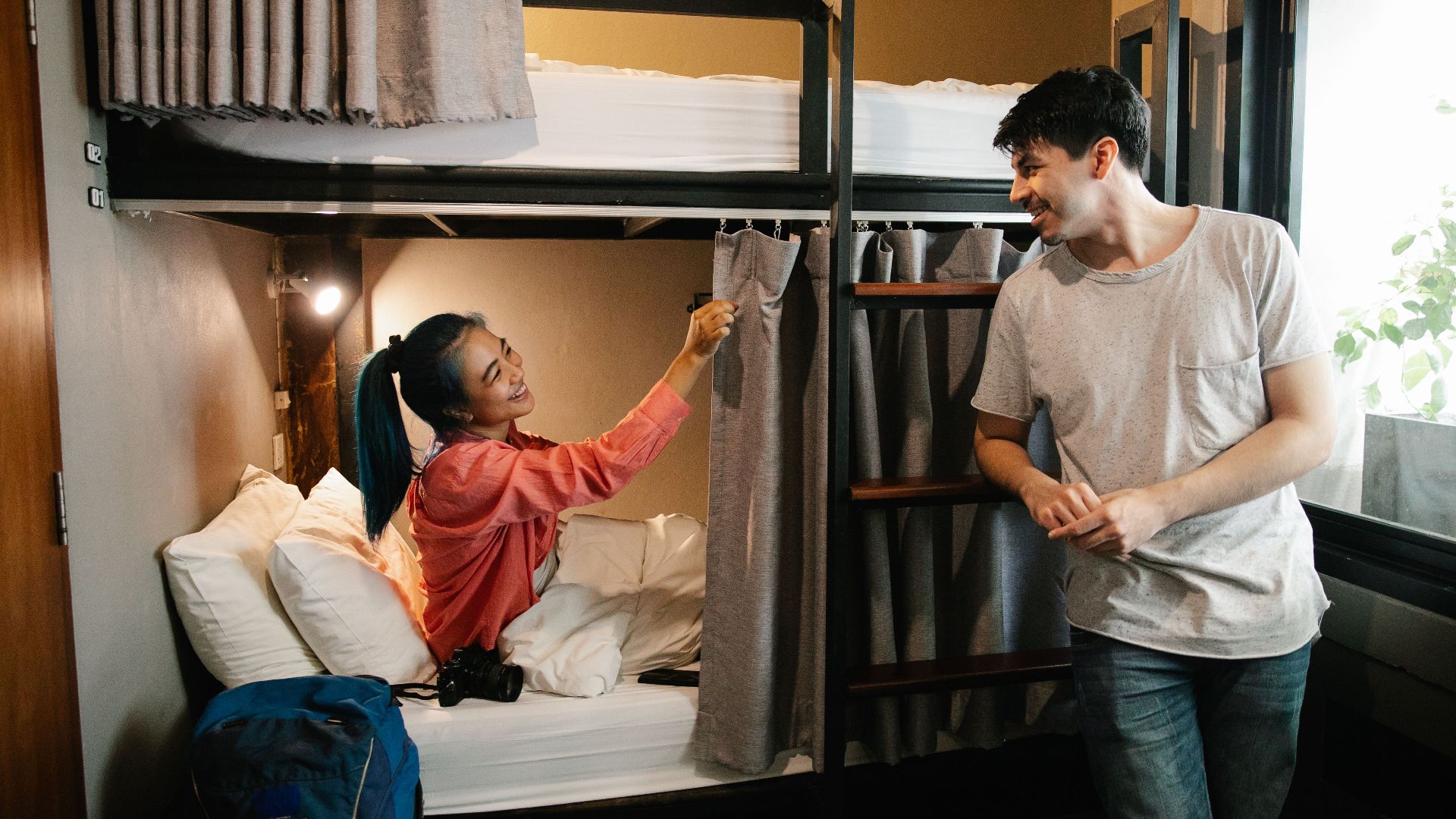 A cheerful moment shared between two friends in a cozy hostel room with bunk beds.