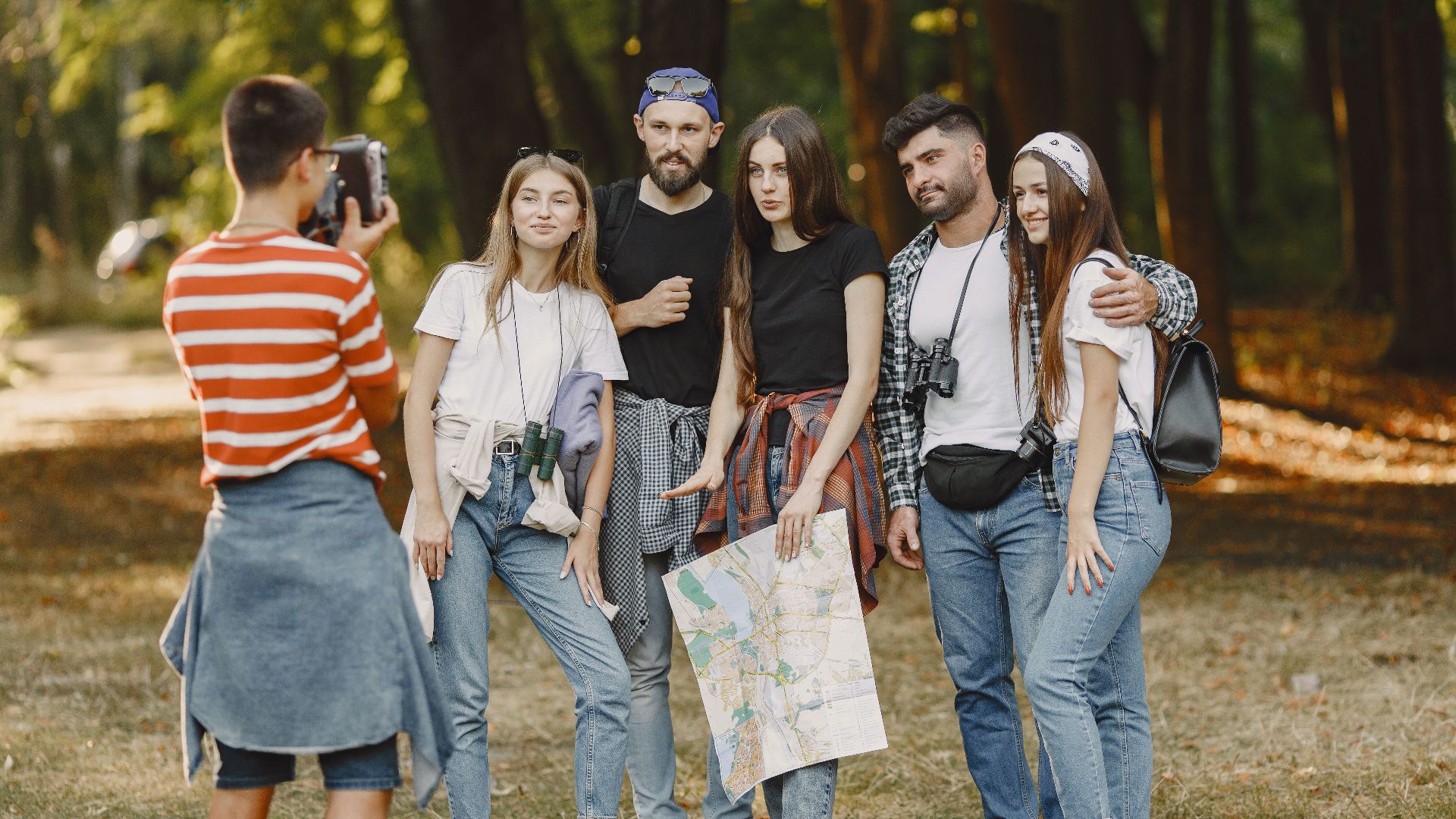 Young friends enjoying outdoor adventure in a forest, posing with a map for a memorable photo.