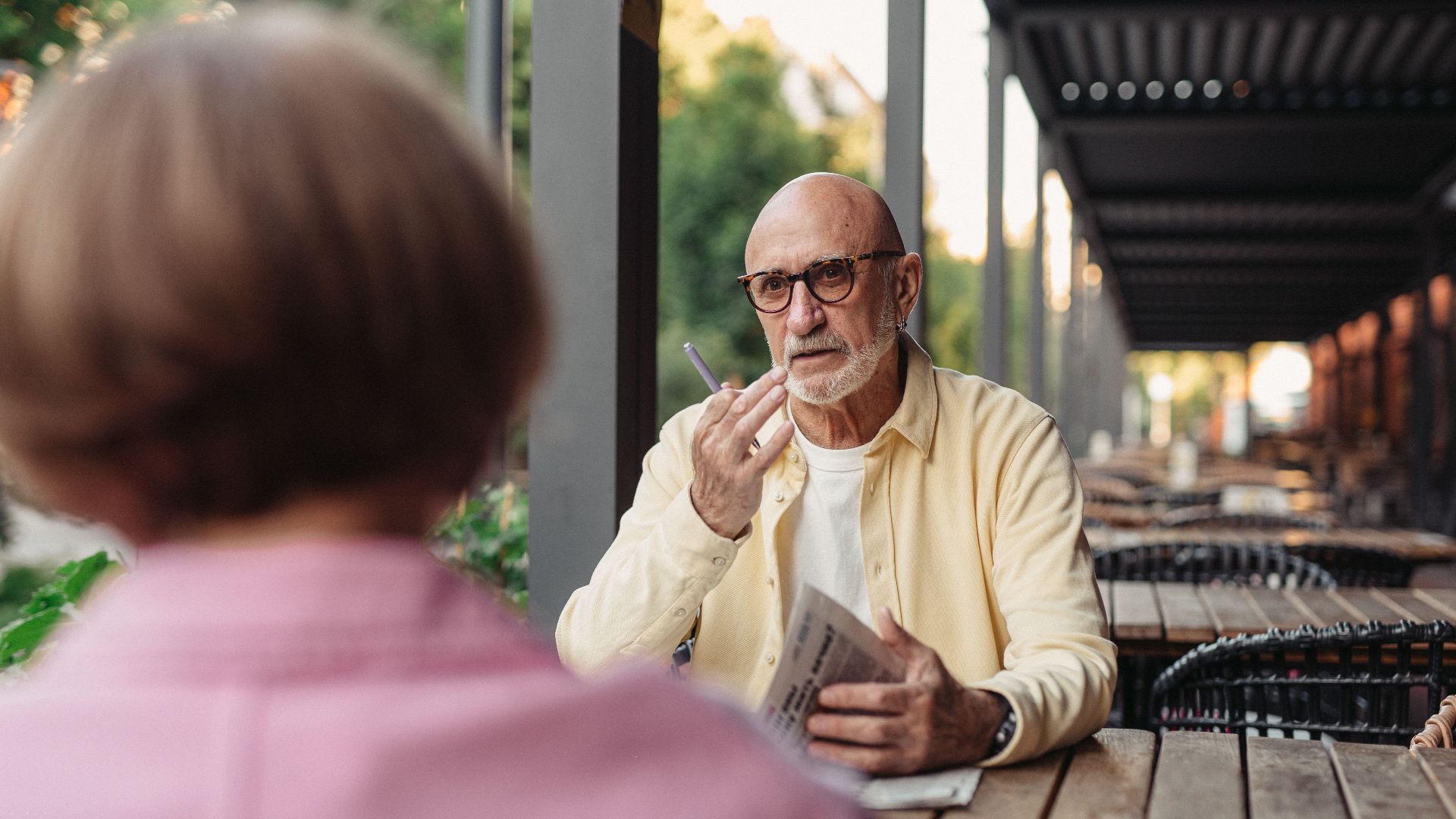 Elderly couple conversing at an outdoor cafe, enjoying a peaceful moment together.