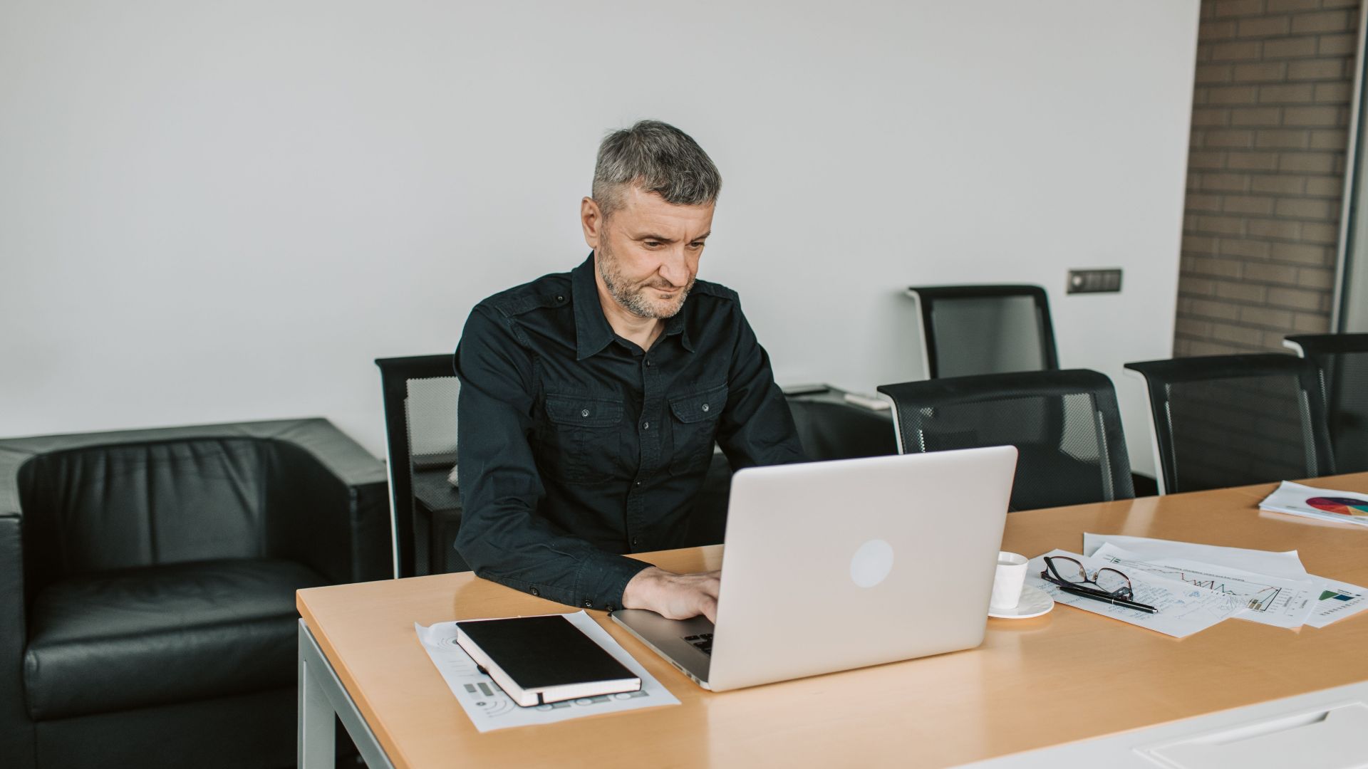 Mature man focusing on his laptop while working in a modern office environment.