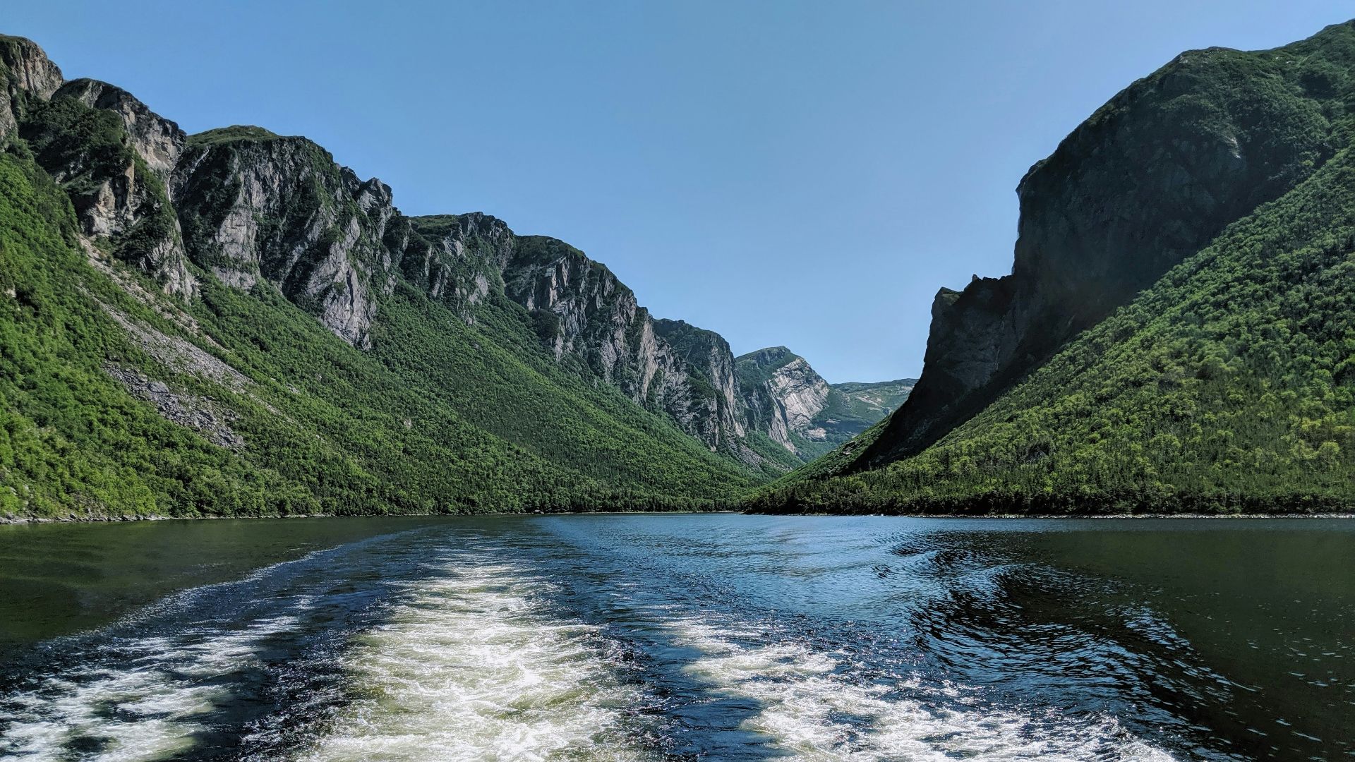 green and gray mountains beside river under blue sky during daytime
