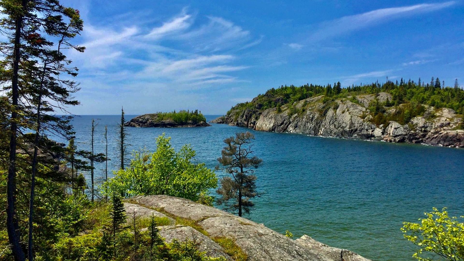 A view across the mouth of Horseshoe Bay as seen on a July 2015 afternoon from the Southern Headland Trail at Pukaskwa National Park, Ontario, Canada. At the mouth of the bay is the roughly two-acre Gull Rock, seen here just left of center with the open w
