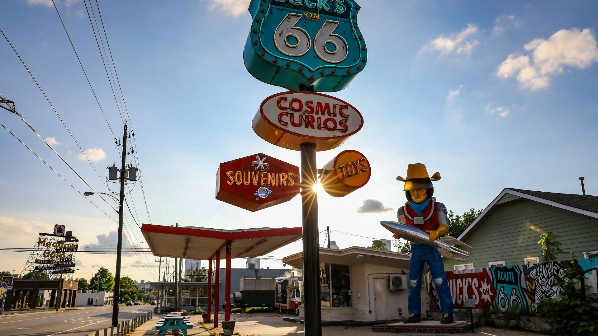 a statue of a cowboy holding a surfboard in front of a gas station