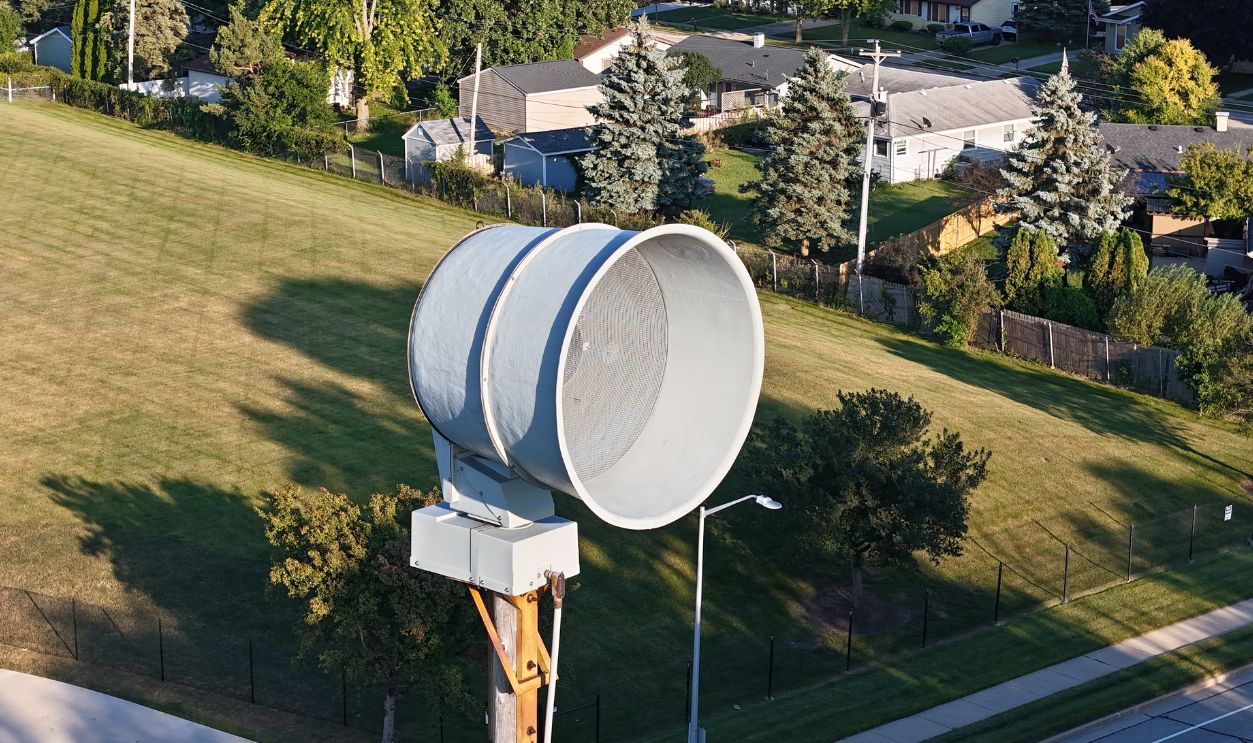 ACA P-50 Tornado Warning Siren Aerial View With The Sun On It Trees Road And Field Backdrop