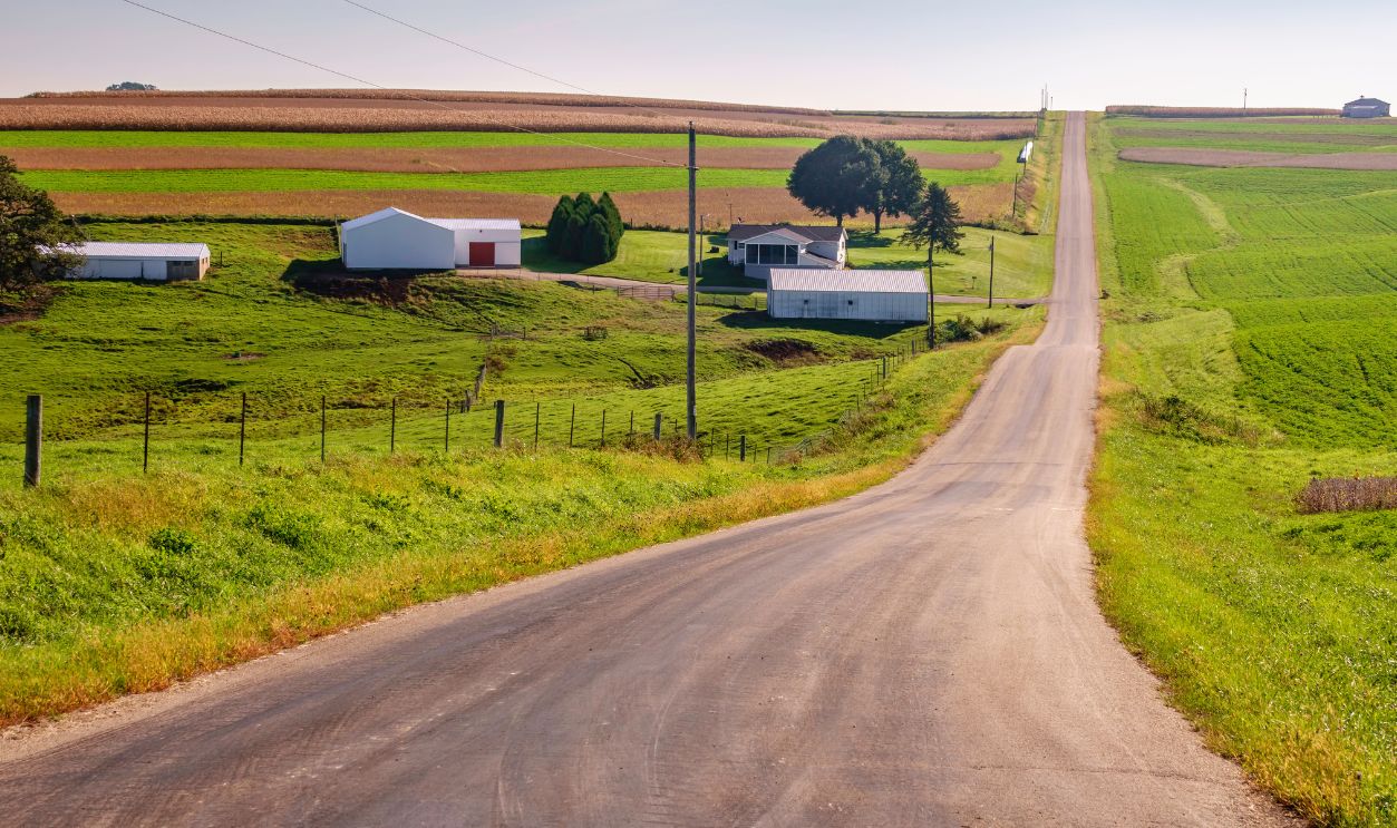 Country road across rolling farmland on a sunny morning early in autumn, southwestern Wisconsin, USA, for rural, agricultural, and travel themes