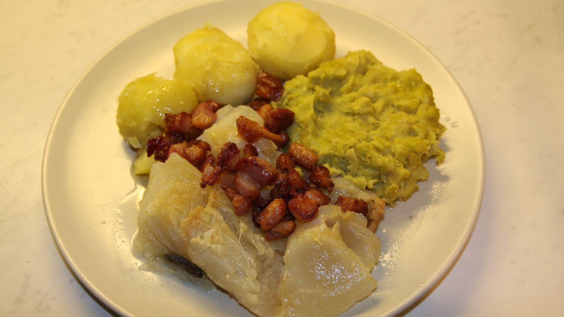 Lutefisk, Tradisjonell, servert med poteter, ertestuing og bacon