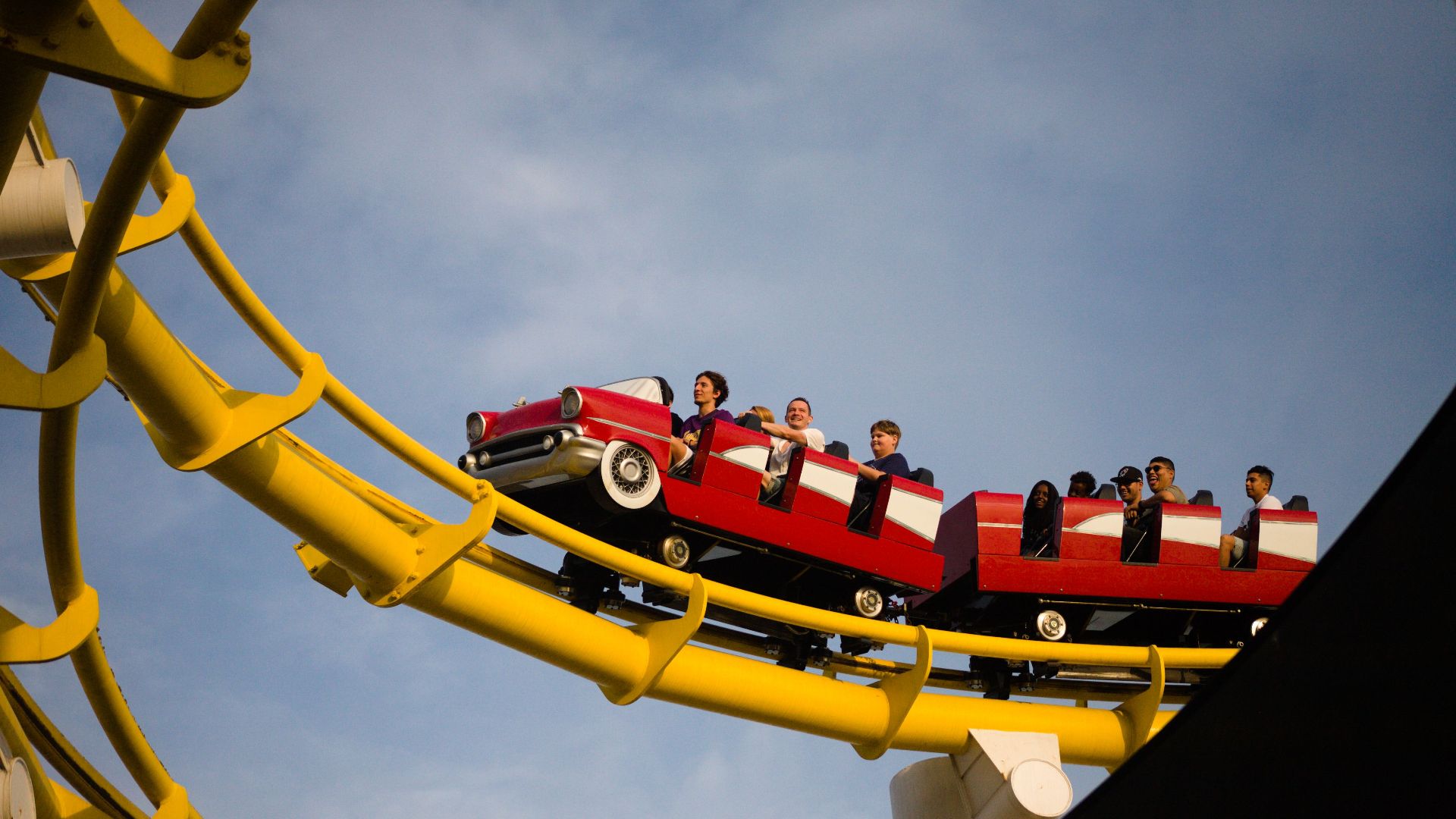 Thrilling roller coaster experience with vibrant red cars on sunny day.