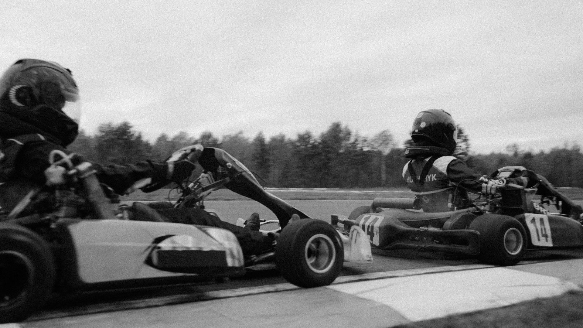 Close-up of racers competing in a high-speed go-kart race on an outdoor track.
