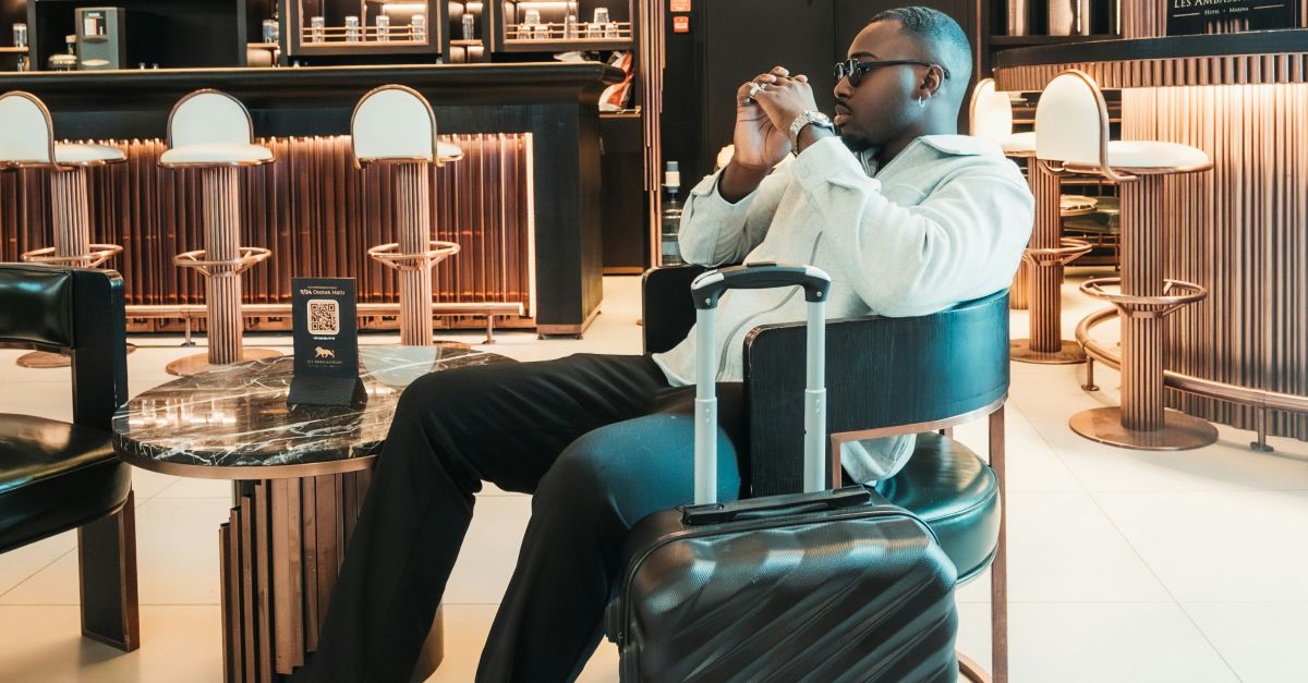 Man sitting with suitcase in stylish hotel lobby
