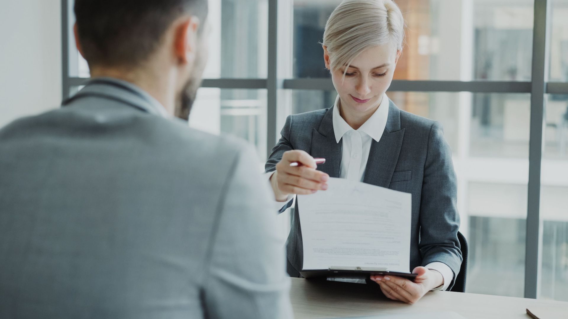 Business professionals reviewing a contract in a modern office setting.