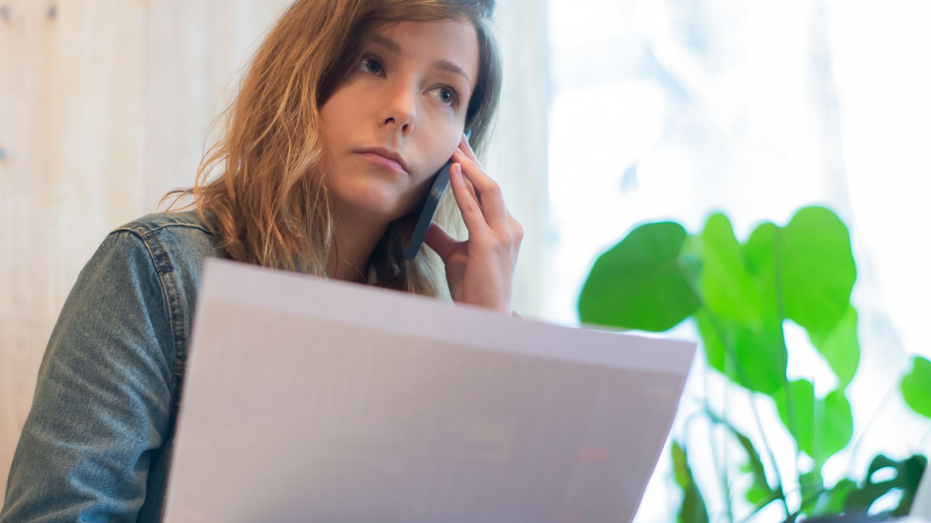 Focused businesswoman reviewing documents in a bright office with natural light.