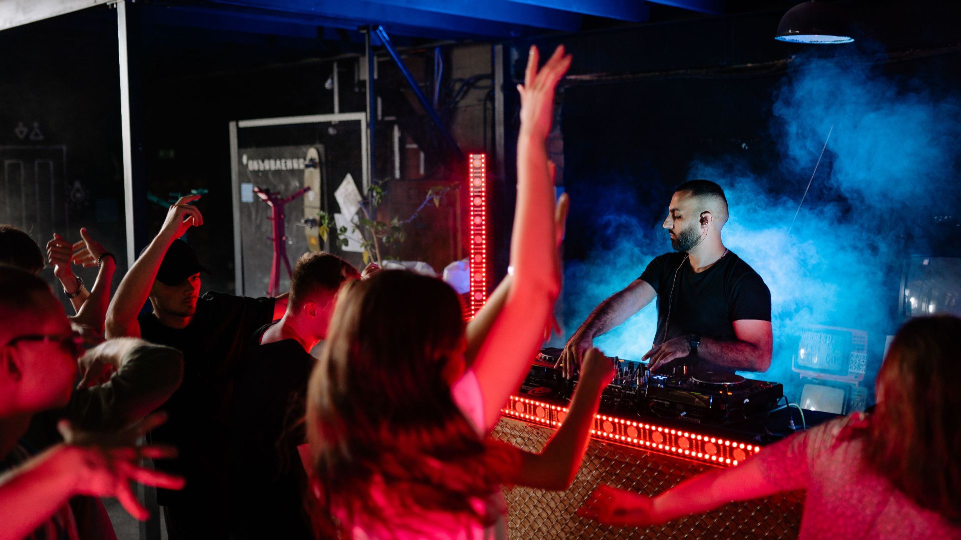 Exciting nightclub atmosphere with a DJ and enthusiastic crowd enjoying the music.