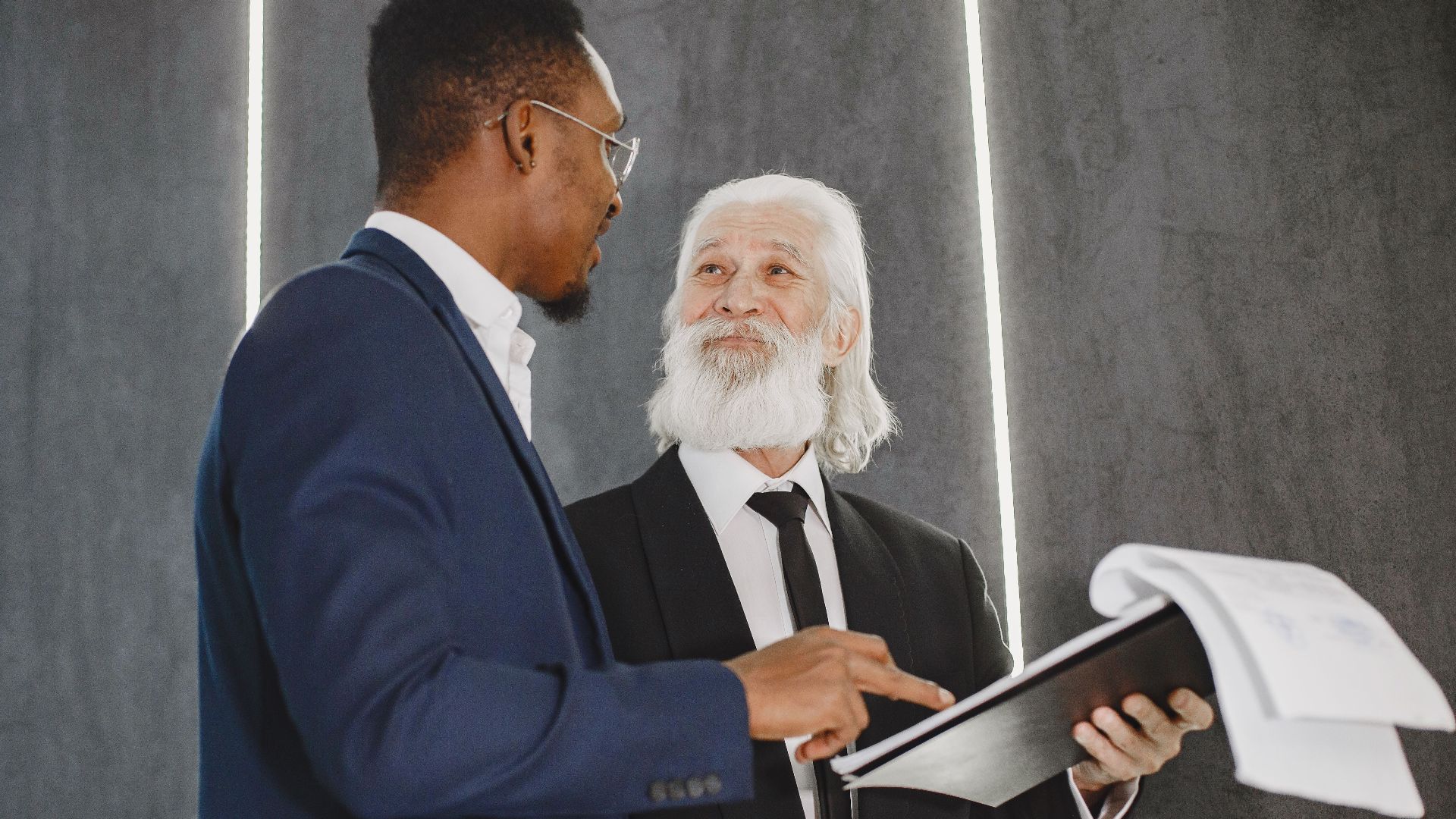 Two businessmen discussing documents in a modern office setting, highlighting professional diversity.