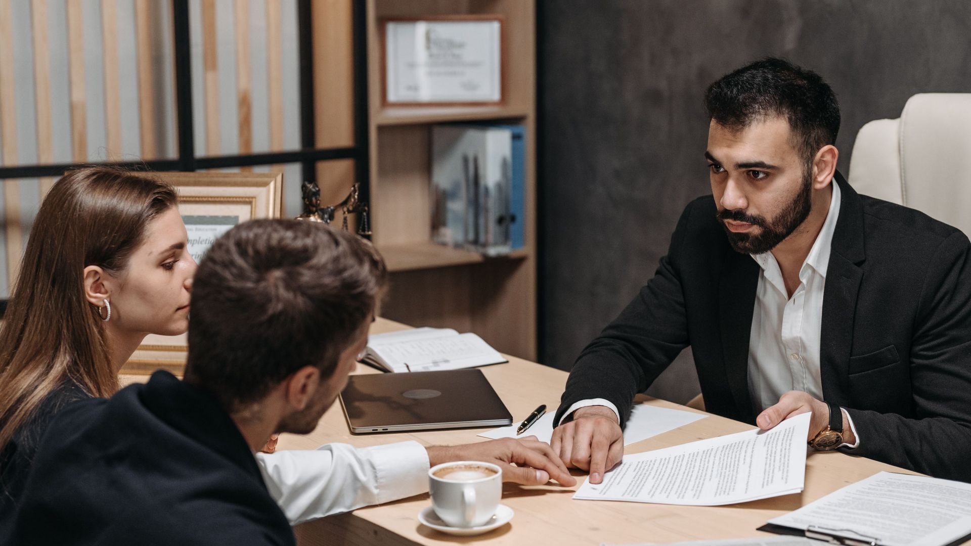 Lawyer discussing legal documents with clients at office desk.