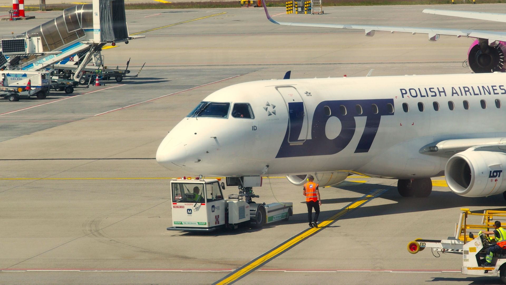 LOT Polish Airlines aircraft being serviced on the tarmac at an airport.