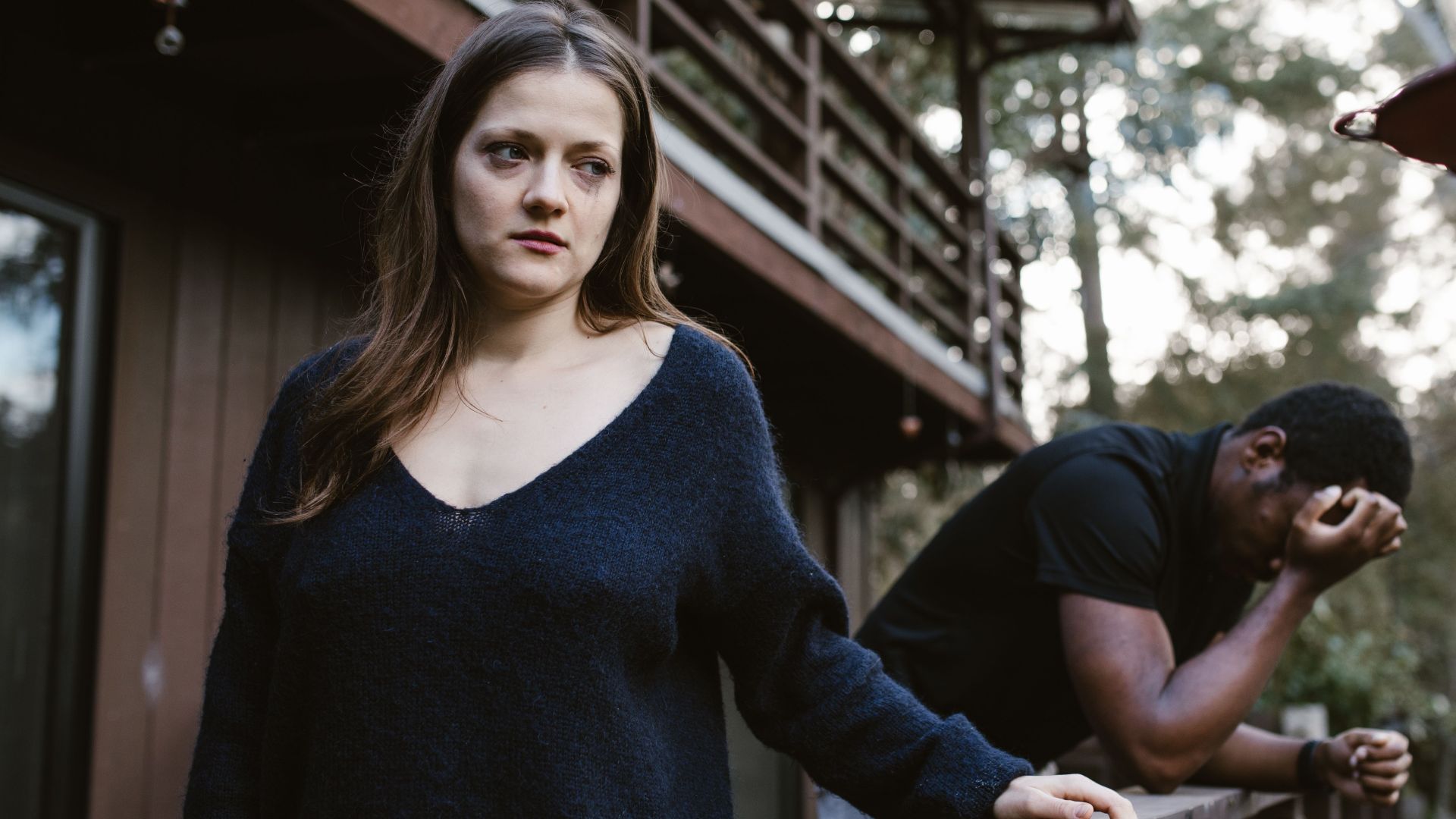 A woman and a man in emotional distress on a balcony, expressing tension.