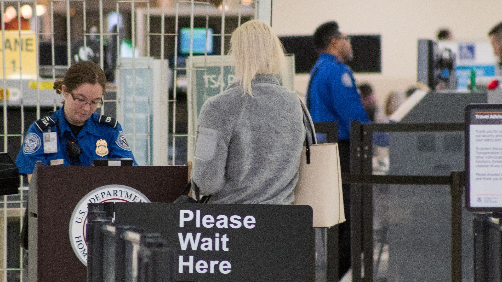 A Transportation Security Administration agent at a checkpoint verifying passenger identification, John Glenn Columbus International Airport
