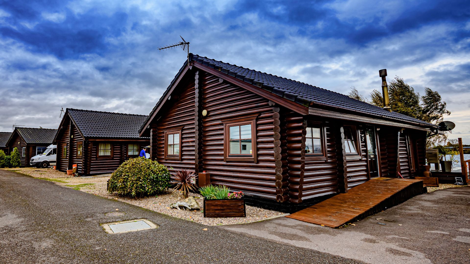 Charming wooden log cabins with a beautiful dramatic sky backdrop in a serene setting.