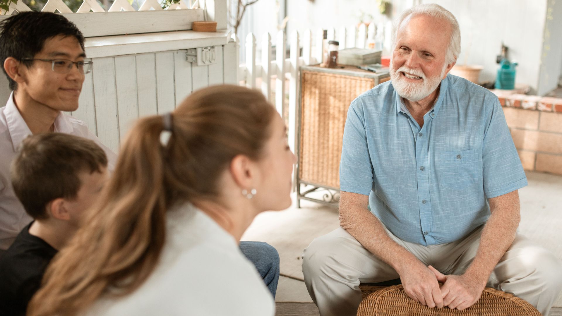 Elderly man enjoying a pleasant family gathering outdoors with diverse group sitting together.