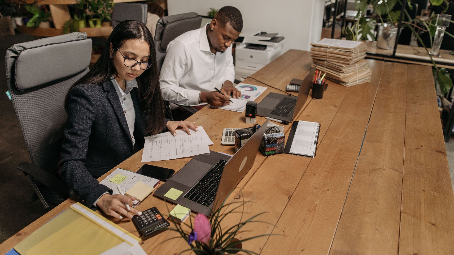 Asian woman and African American man working with laptops in a modern office setting. Collaboration and teamwork.