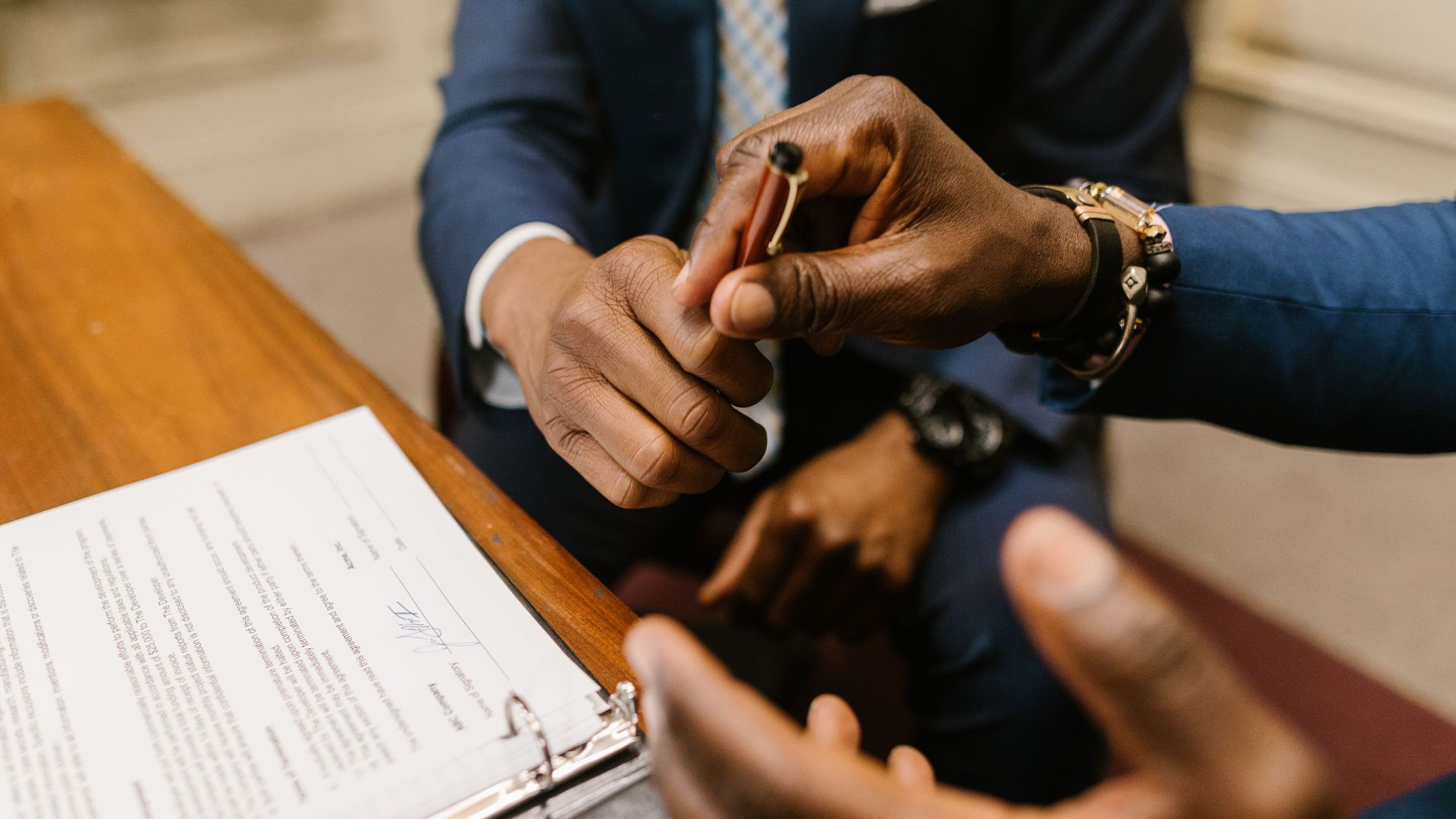 Two businessmen in suits finalize a contract, highlighting teamwork and agreement.