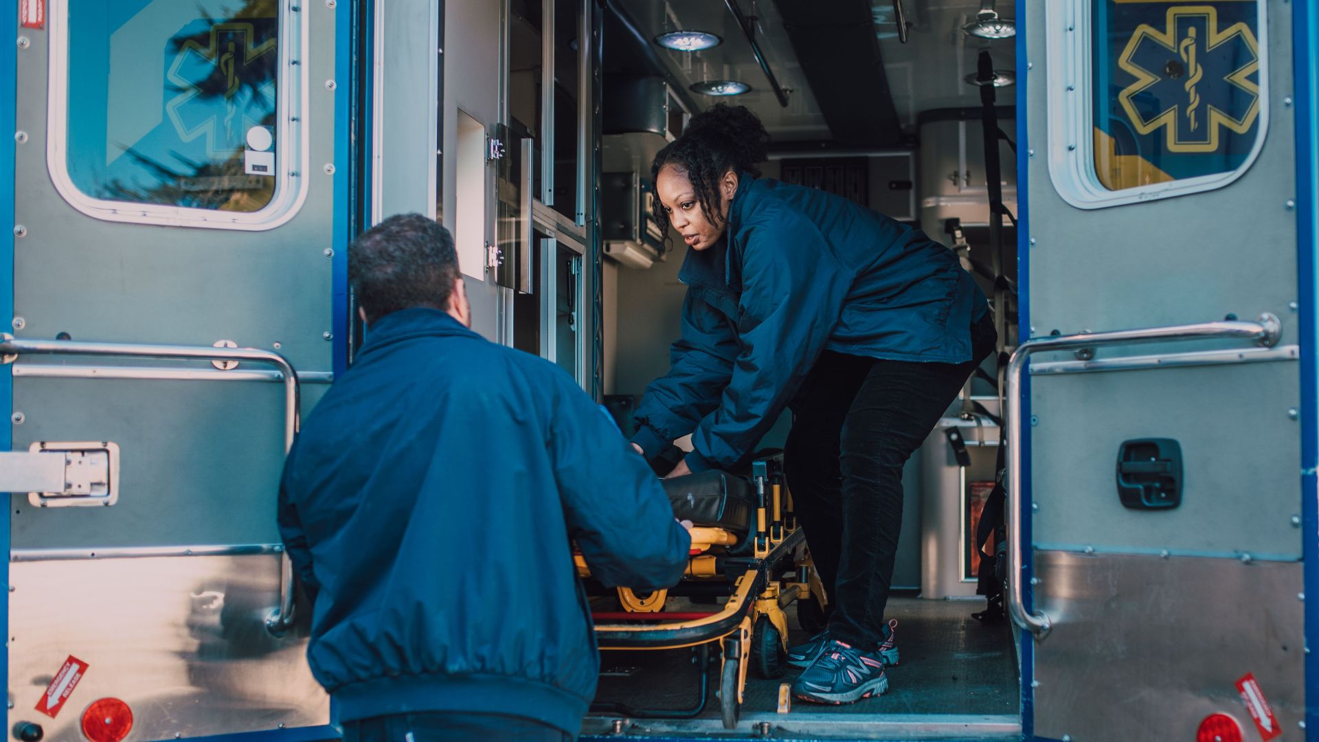 Two paramedics load a stretcher into an ambulance, ready for emergency medical service.