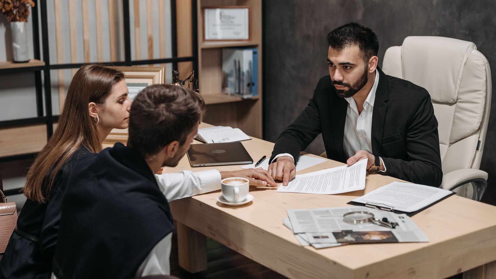 Lawyer discussing legal documents with clients at office desk.