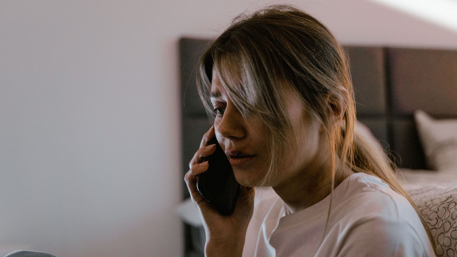 A worried woman on a phone call indoors, conveying stress and emotion.