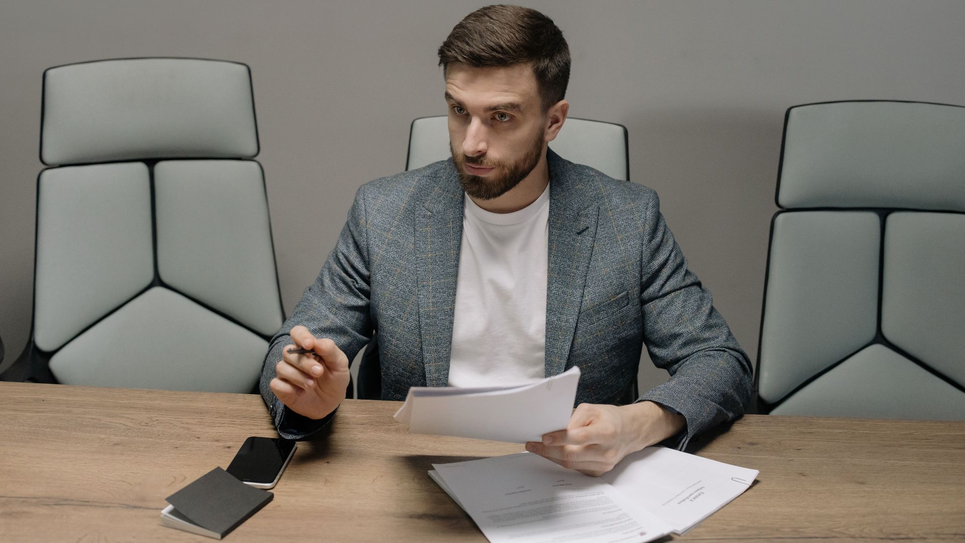 Professional businessman in a suit holding documents during a meeting in an office setting.