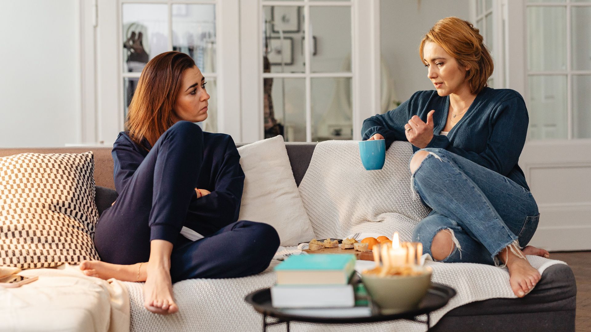 Two women having a heartfelt conversation, enjoying a cozy moment in a modern living room.