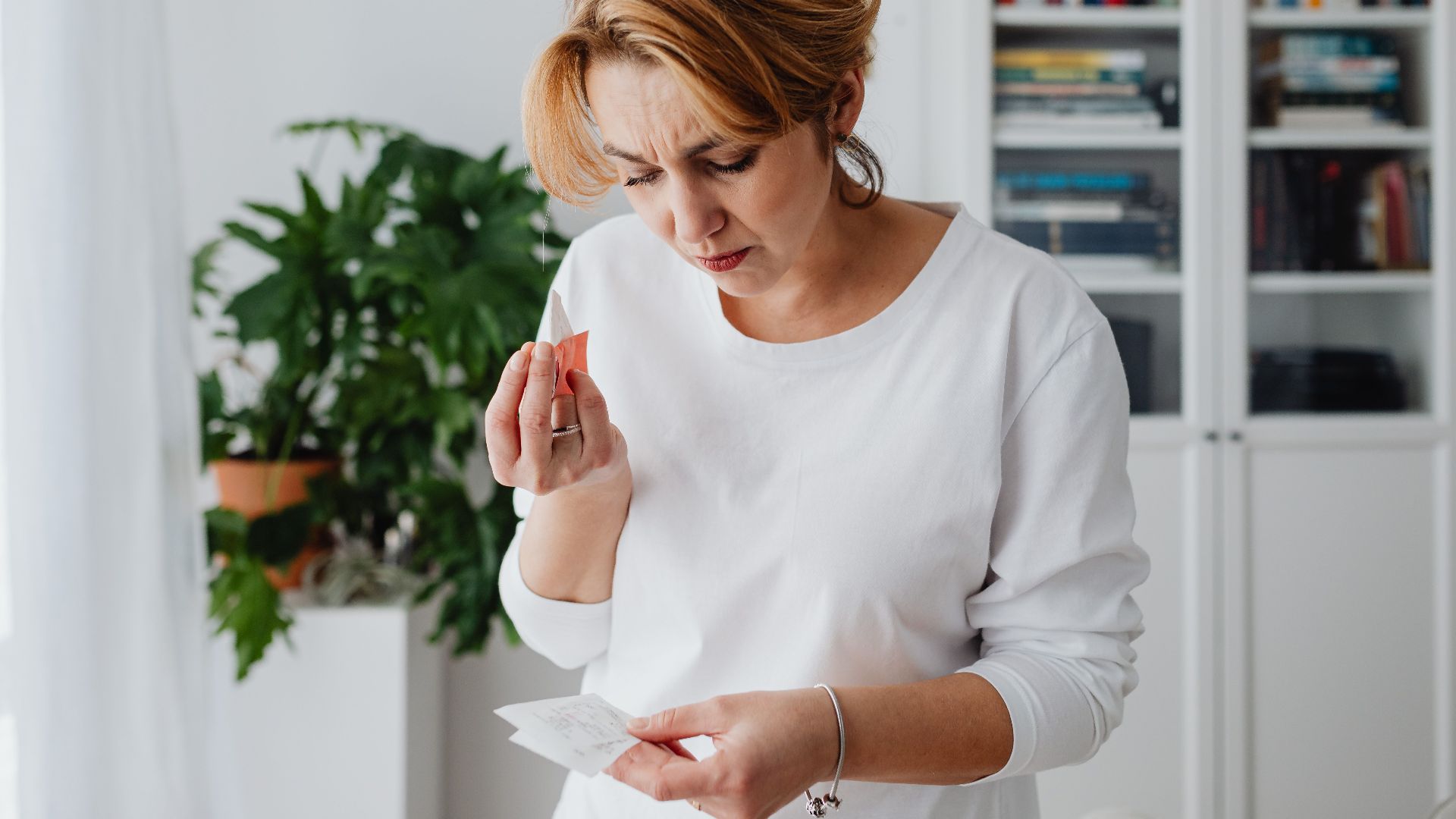 A concerned woman checks her bills, reflecting financial anxiety and budgeting challenges.