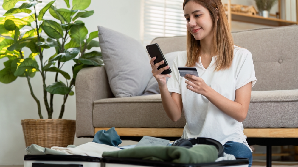 Happy young woman with credit card booking vacation
