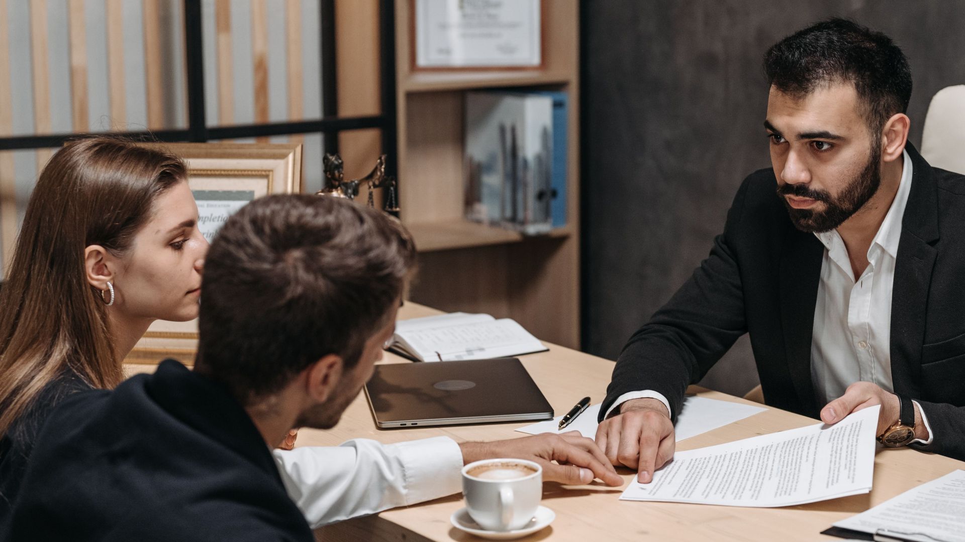 Lawyer discussing legal documents with clients at office desk.