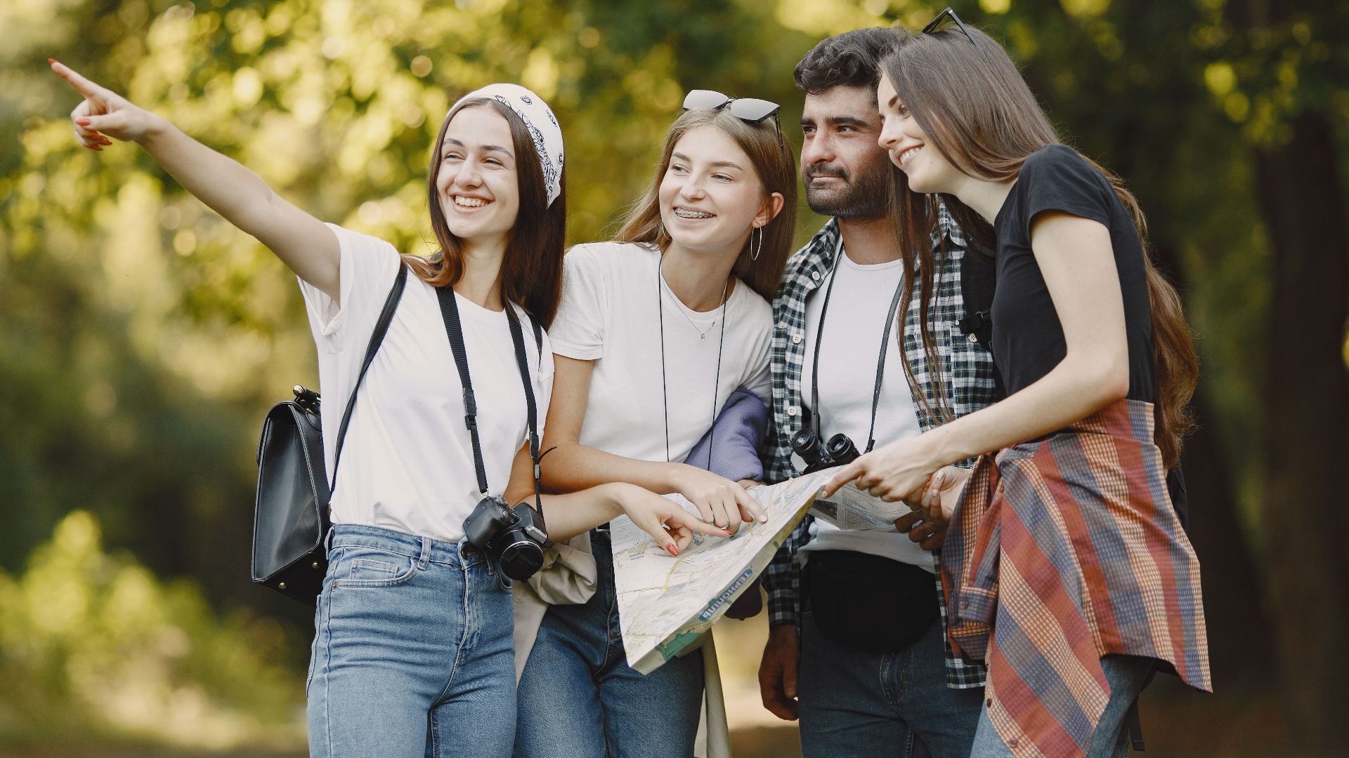 Young friends exploring a park with a map, smiling and enjoying the outdoors.